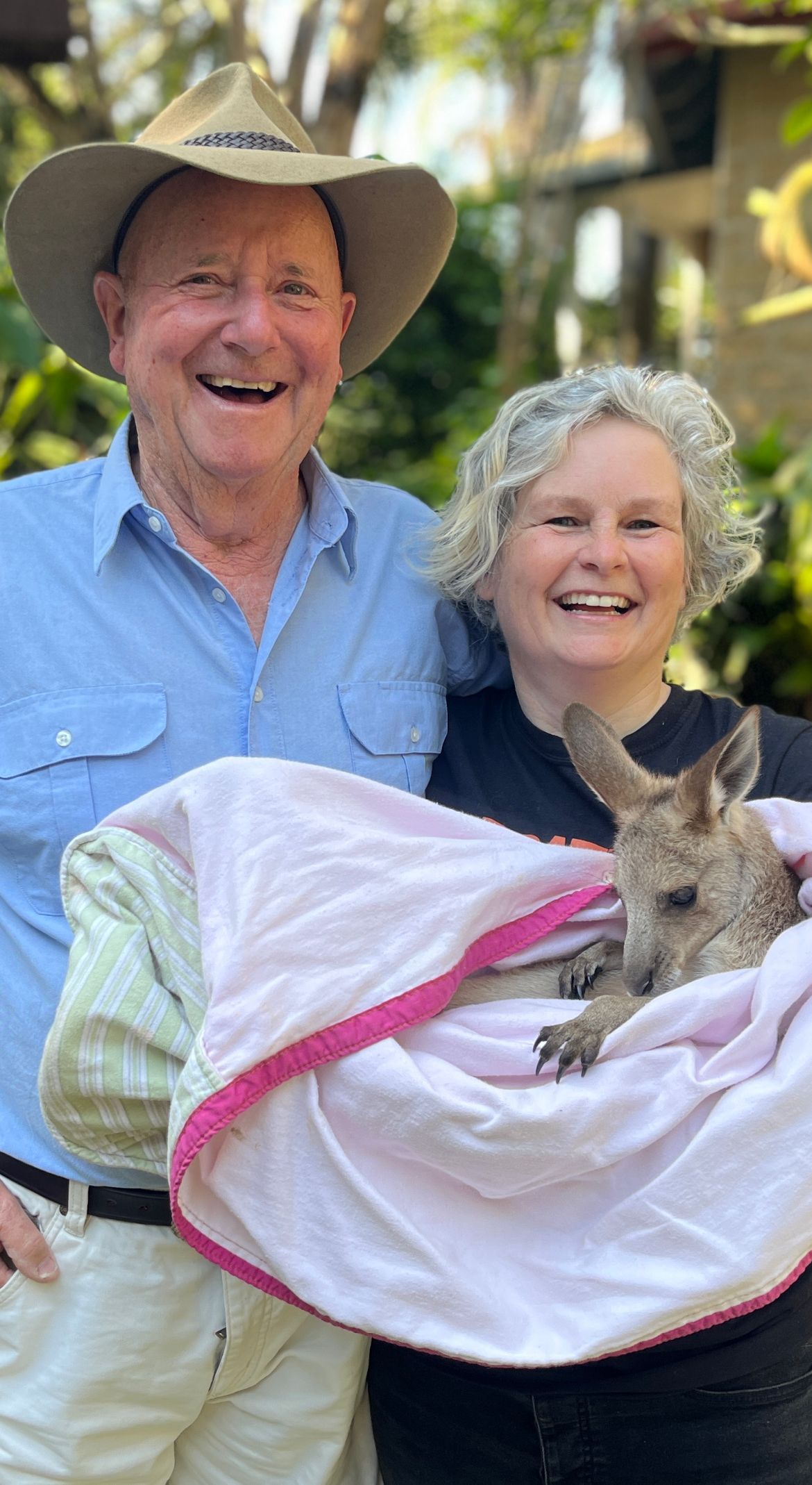 A man and woman smiling with a joey