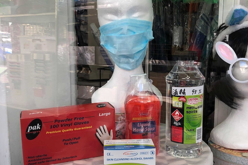 Mannequin in a face mask, displayed next to a box of gloves, a bottle of liquid hand soap and methylated spirits.