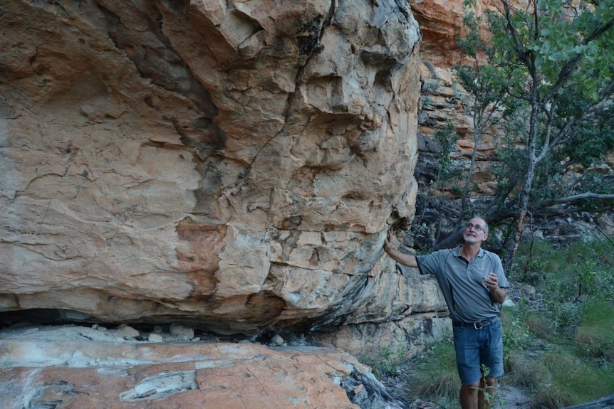 Man leans against weathered rock formation, admiring it