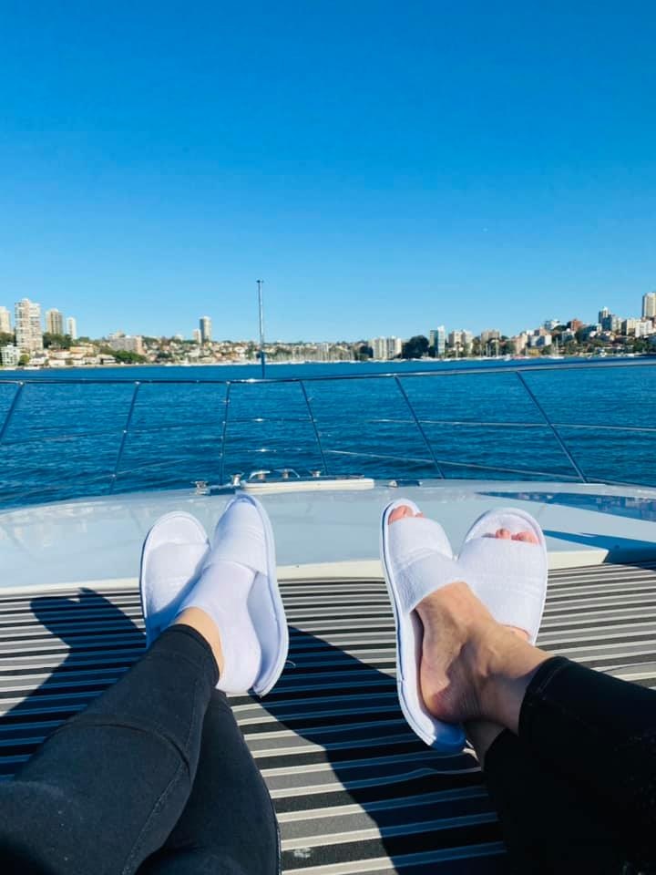 A view of two pairs of feet in slippers stretched out on a boat on Sydney Harbour.