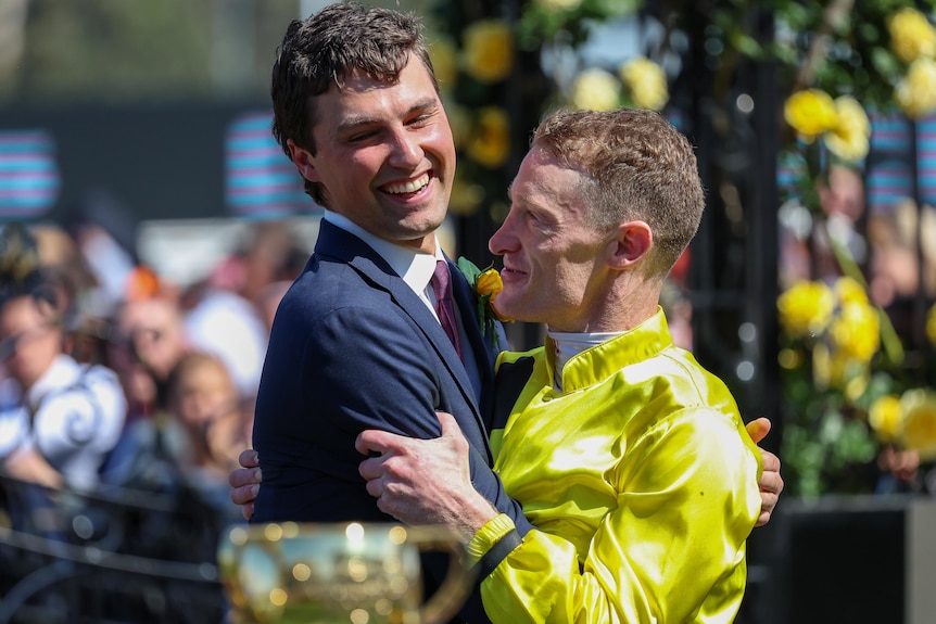 Two men hug after a horserace