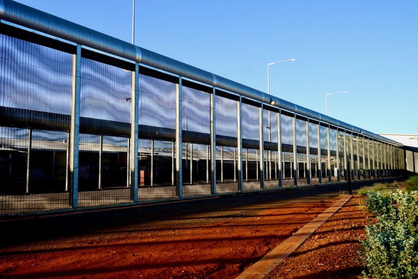 A fence around a prison beneath a clear sky.