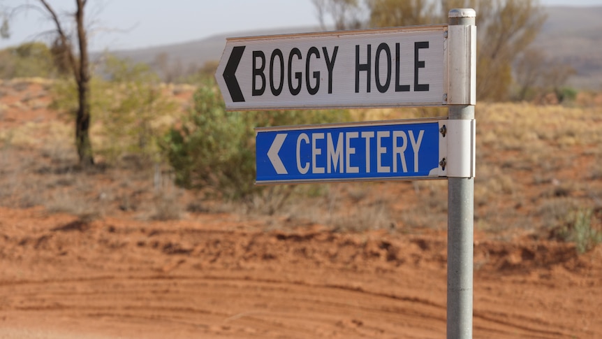boggy hole and cemetery road signs near a red dirt road
