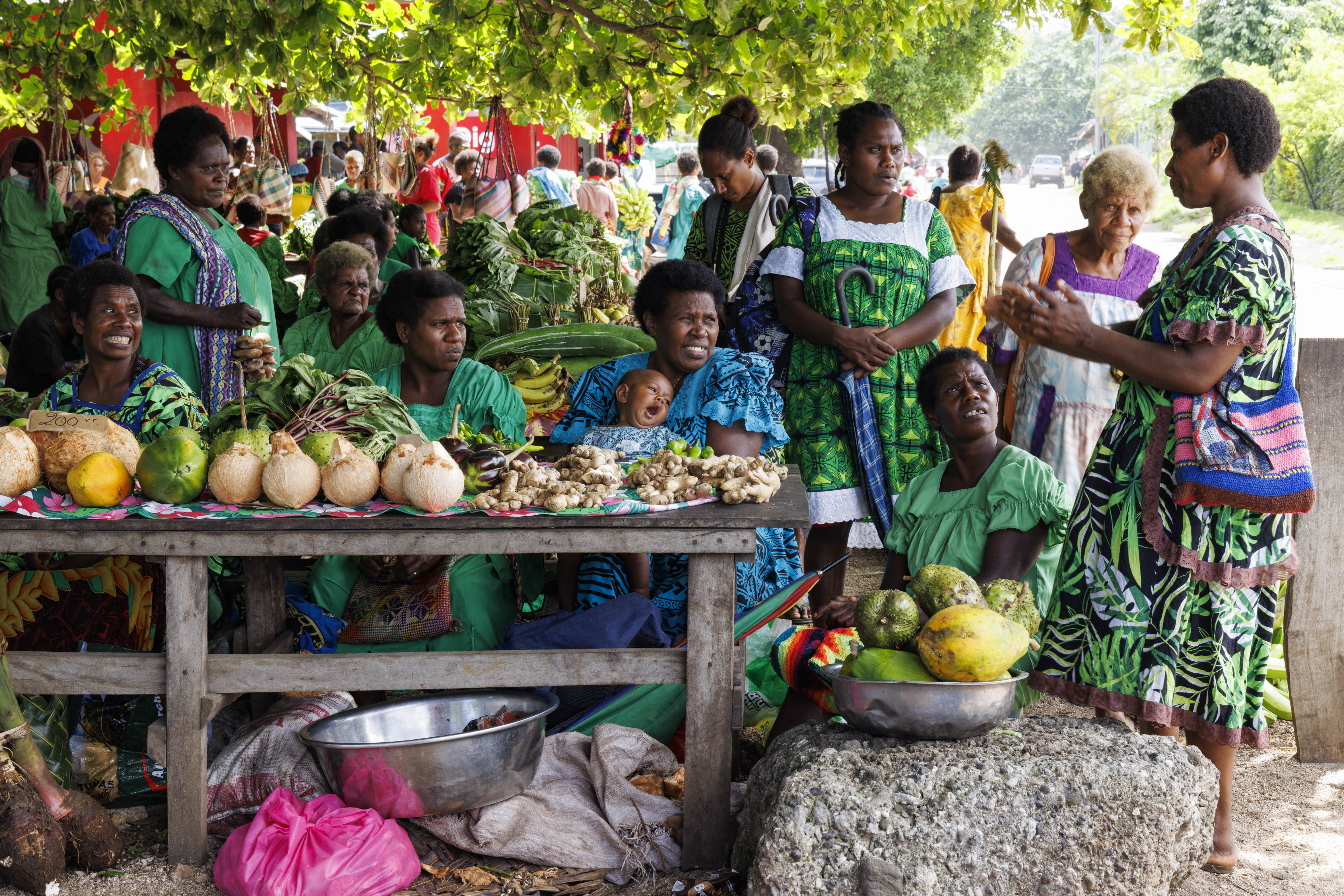 Woman and children huddle around a market stall.