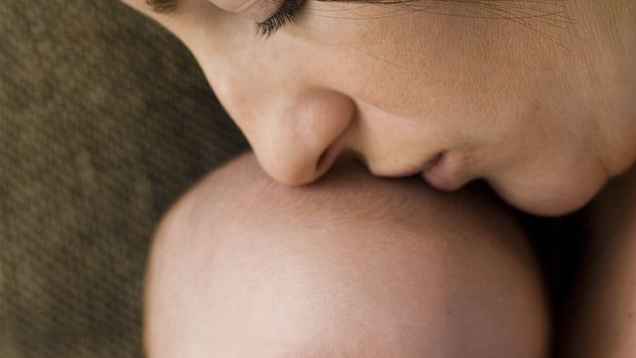 Mother kissing the top of her baby child's head