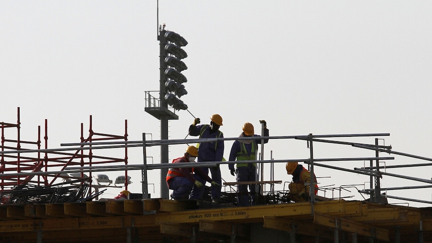 Migrant labourers work at a construction site in Doha