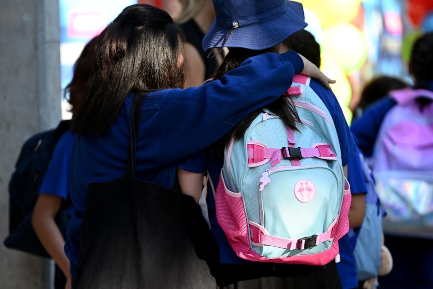 a young female student hugging another young female student
