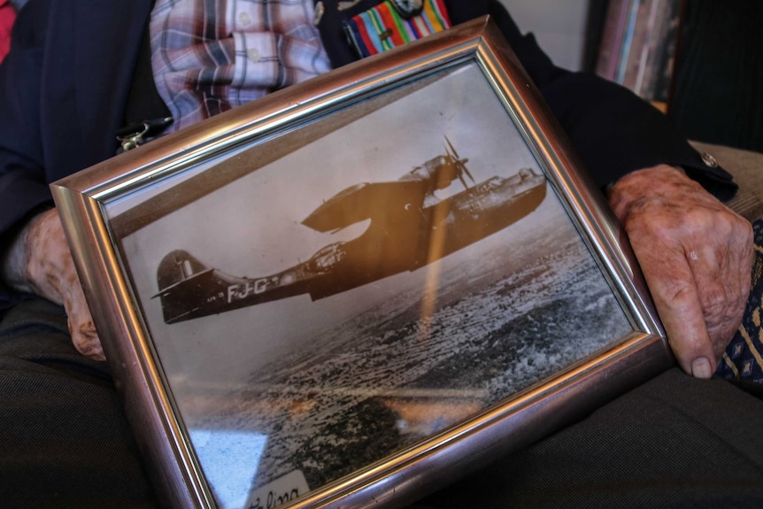 Keith Farrell holds picture of war plane