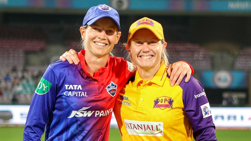 Delhi Capitals captain Meg Lanning and UP Warriorz captain Alyssa Healy stand with their arms around each other.