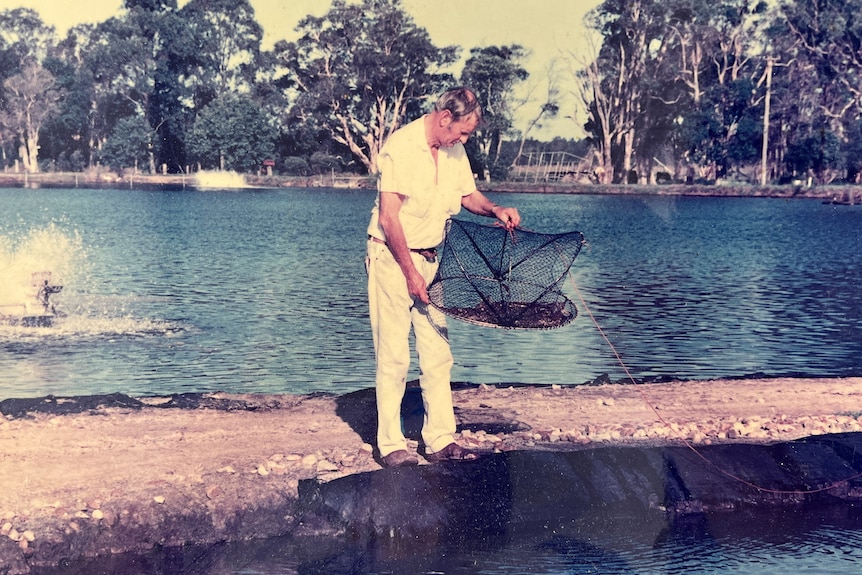 man holding fishing net standing next to large prawning pond near Clarence River