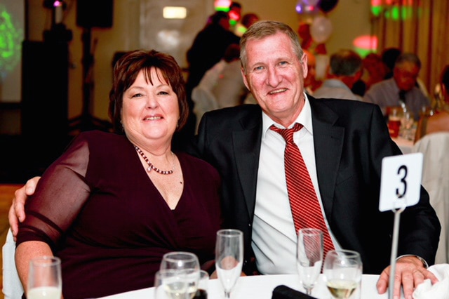 Glenys and Kevin Forbes smiling while sitting at a table at a function.
