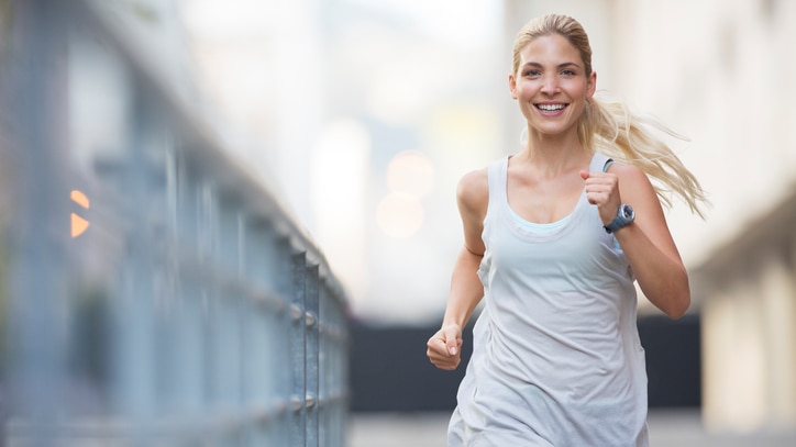 A girl jogging in the city with a smile on her face