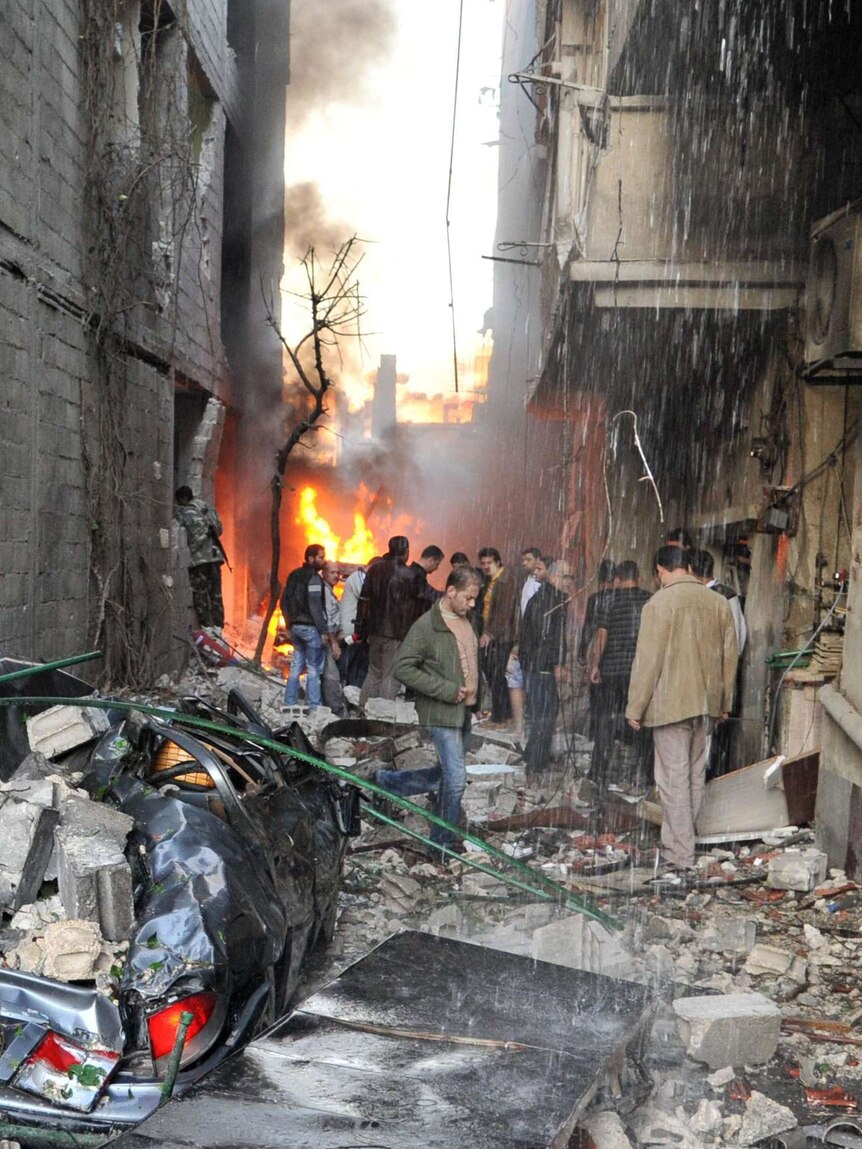 Syrian men inspect the scene of a car bomb explosion in Jaramana, a suburb of Damascus.