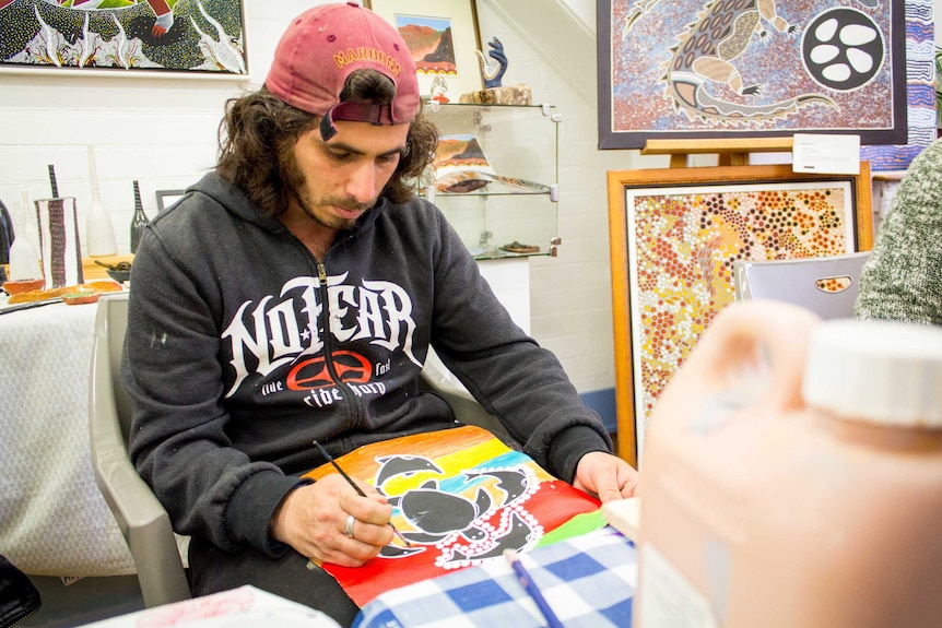 Patrick Anderton paints at a table.