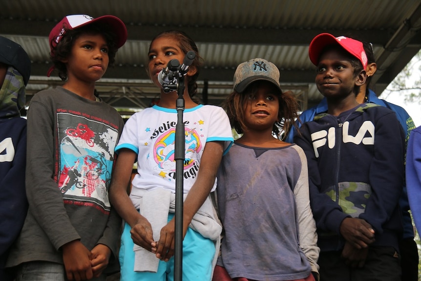 Four children stand by a microphone
