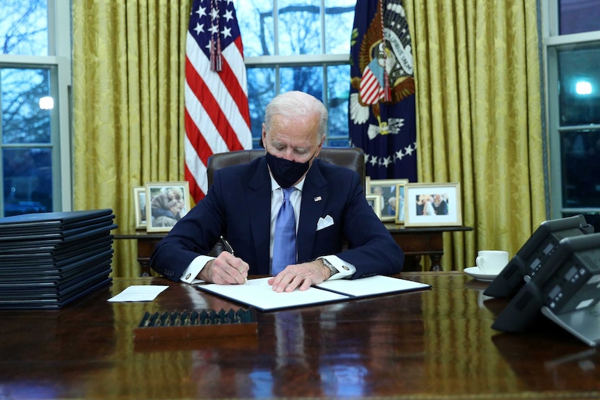 US President Joe Biden signs executive orders in the Oval Office.