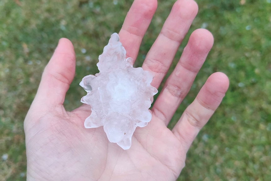 Large jagged hailstone in a hand. 