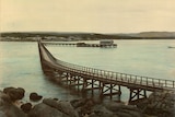Old image of a causeway leading back to the mainland with pier abutting from it.