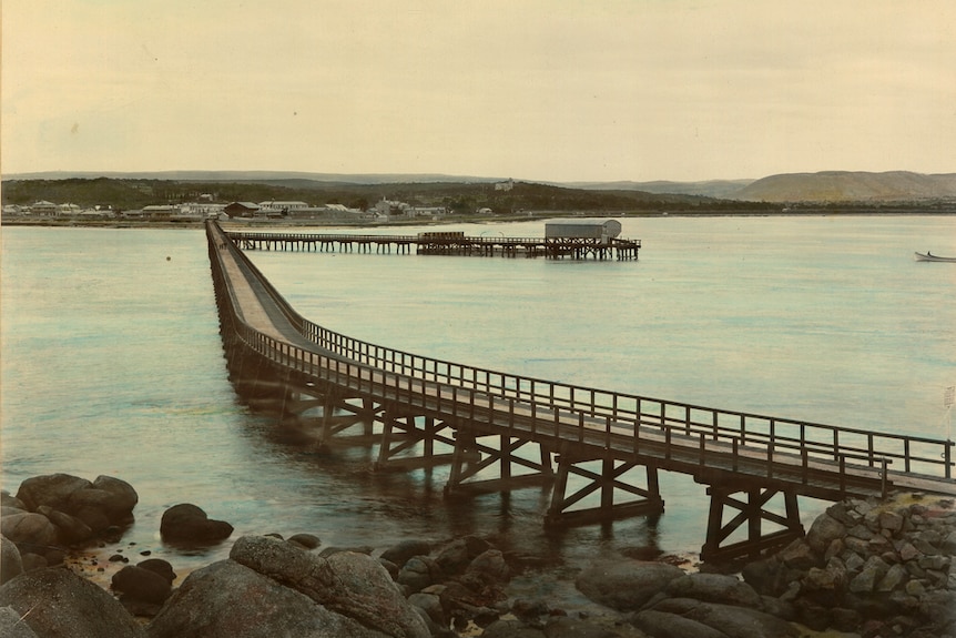 Old image of a causeway leading back to the mainland with pier abutting from it.