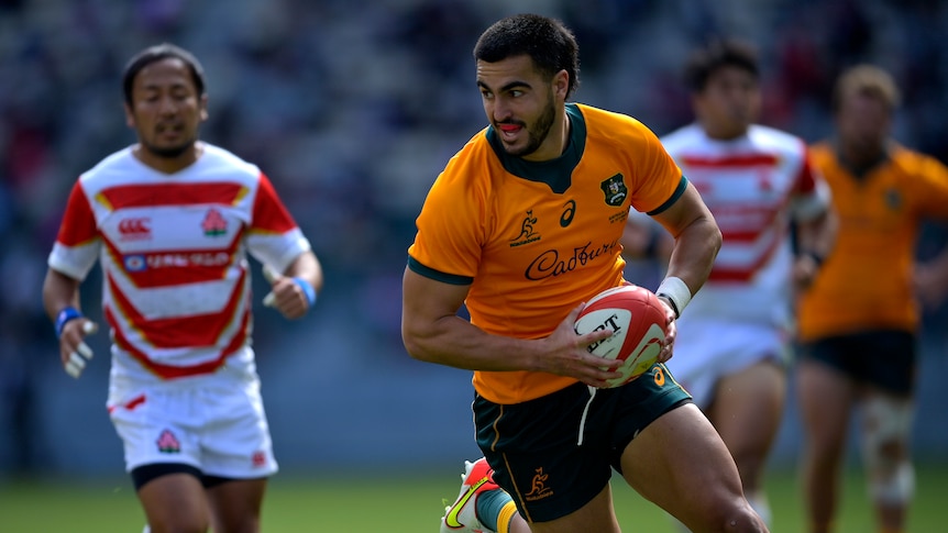 A Wallabies player runs with the ball as he is about to score a try against Japan.