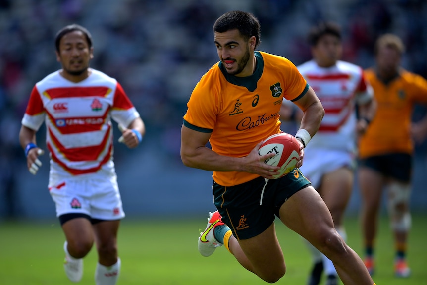 A Wallabies player runs with the ball as he is about to score a try against Japan.