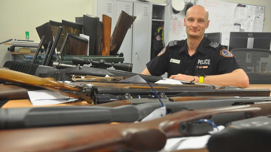 Senior Sergeant Drew Slape with a pile of guns.