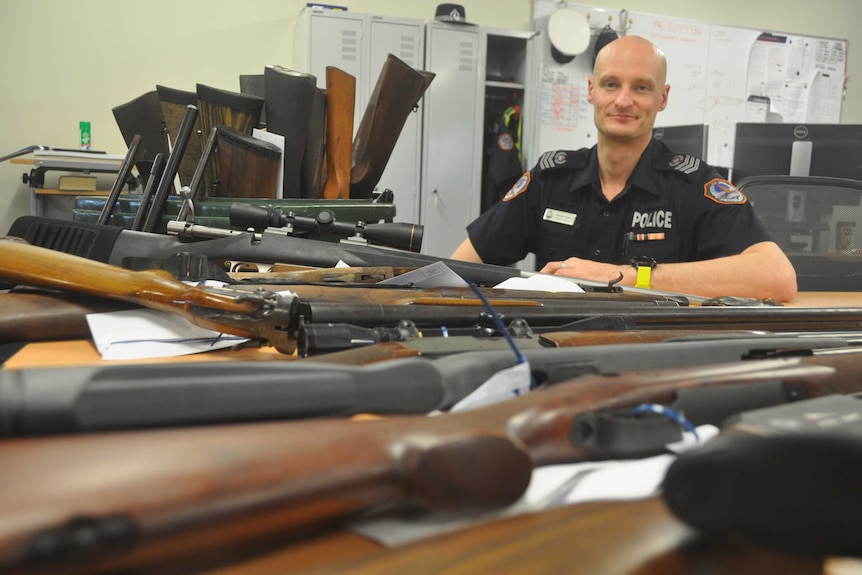 Senior Sergeant Drew Slape with a pile of guns.