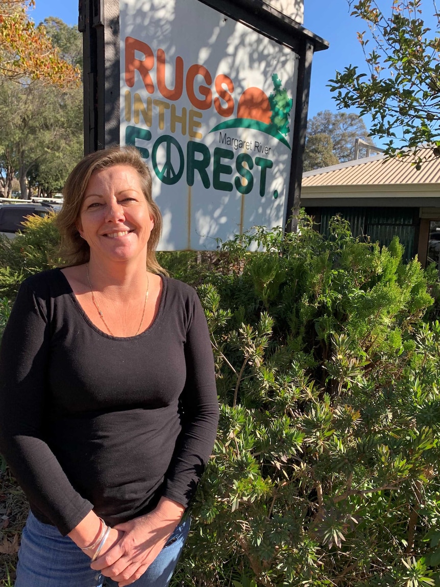 A woman stands in front of the shop sign which reads Rugs in the Forest