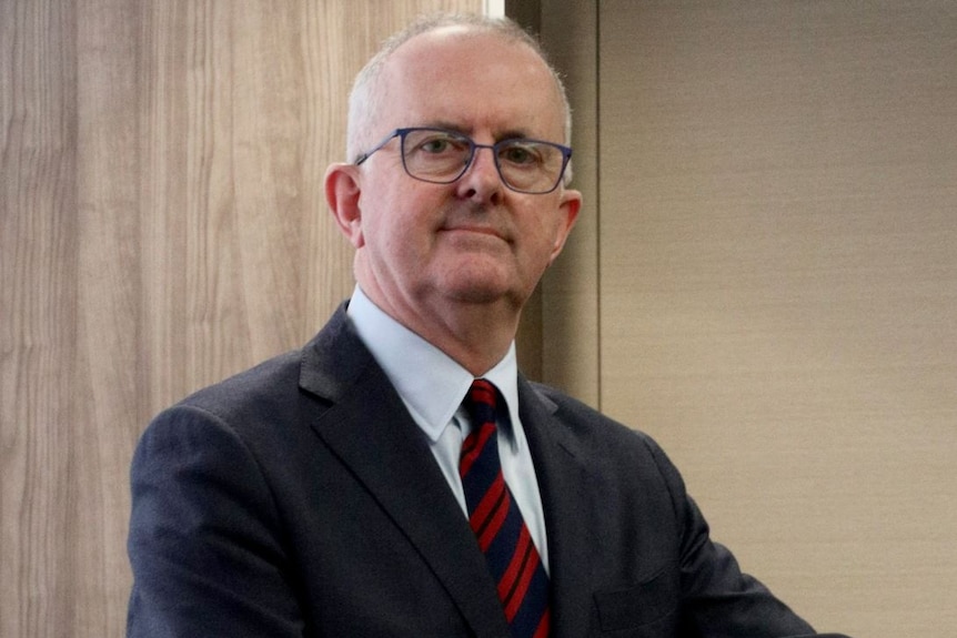 A serious looking, balding man in a suit. 