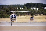 Two water bombing helicopters fill up from a dam near Churchill