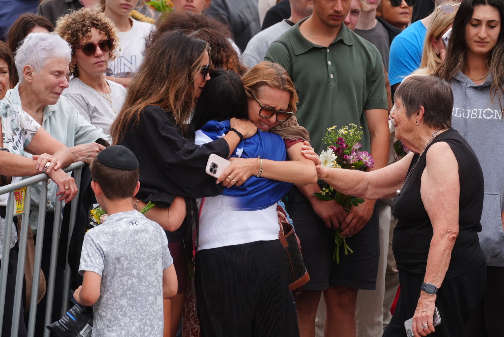Um grupo de mulheres se abraçam e choram