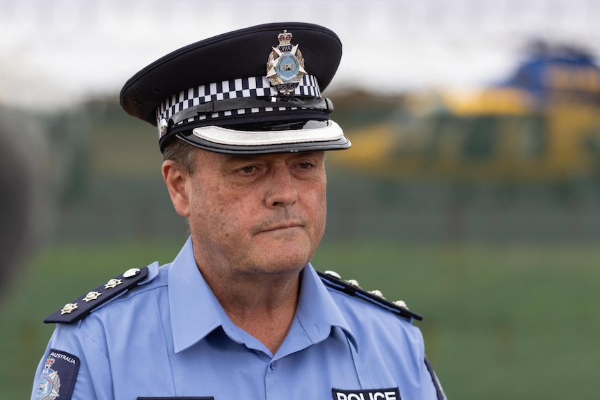 A medium shot of a police officer in uniform with a cap.