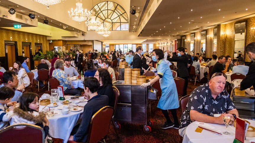 diners sitting at round tables waiting for the food trolley to go past