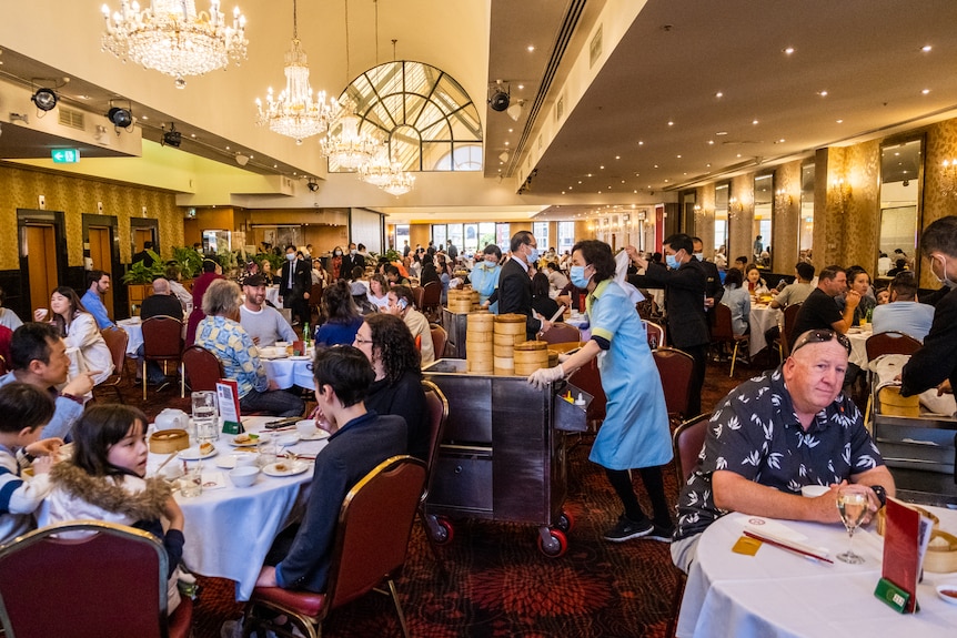 diners sitting at round tables waiting for the food trolley to go past