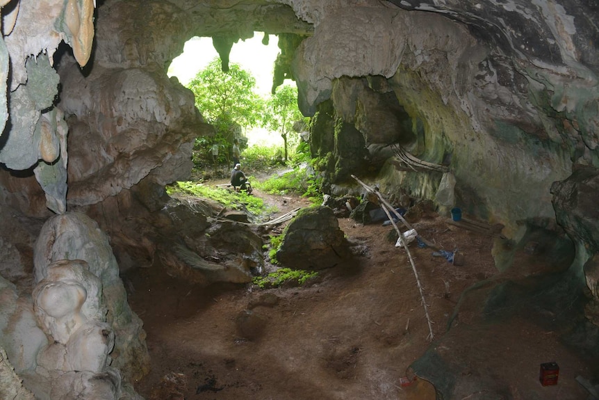 The inside of a cave, with a sandy floor and rock walls