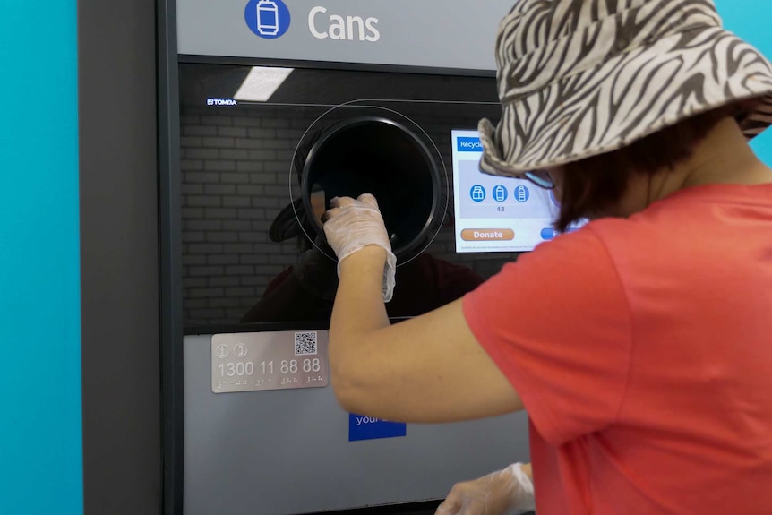 Lady depositing containers into an exchange kiosk.