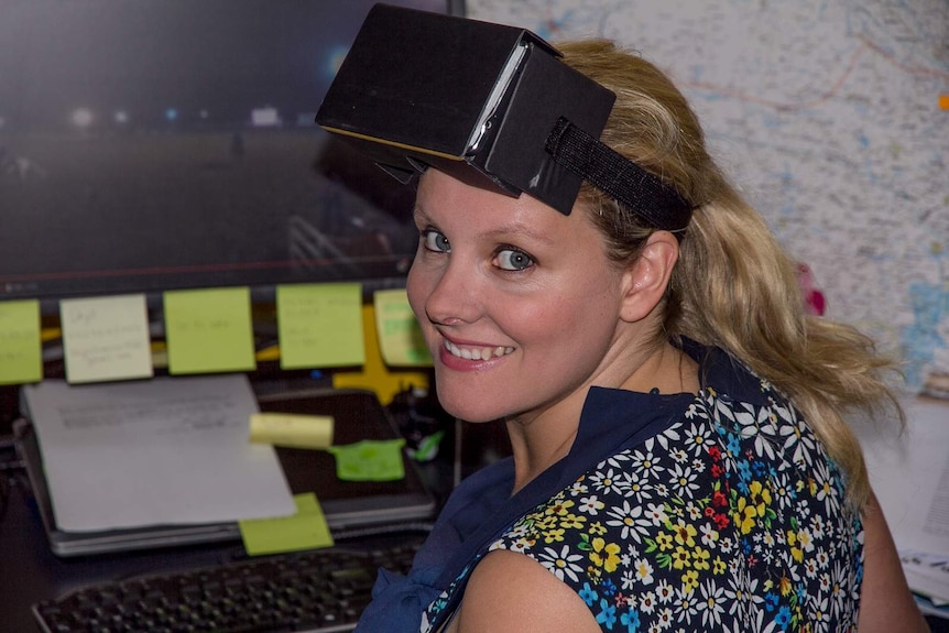 A woman with a black cardboard box strapped to her head - a virtual reality headset