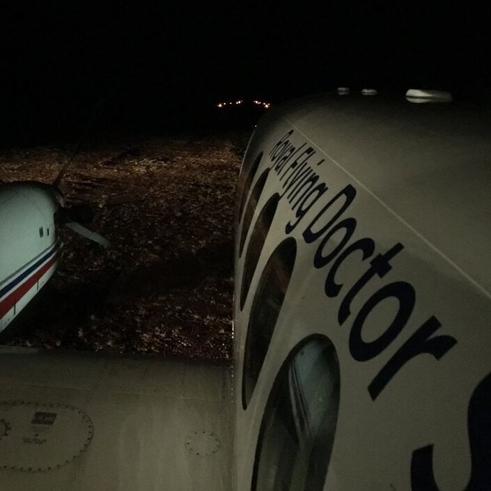 A Royal Flying Doctor Service aircraft landing in a remote location at night.