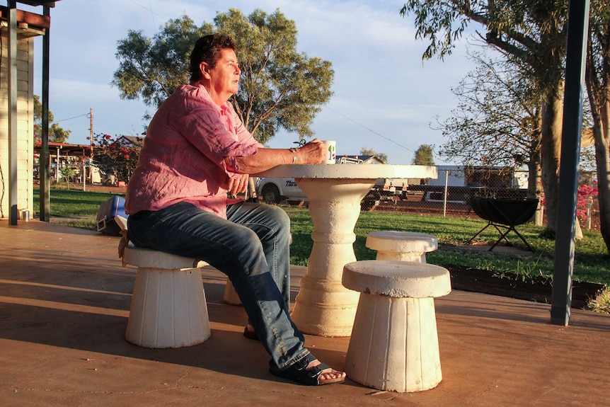 A woman sits with a cuppa in the morning sun.