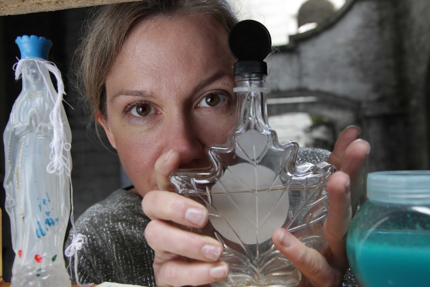Close up of Amy Sharrocks holding a leaf-shaped glass bottle.