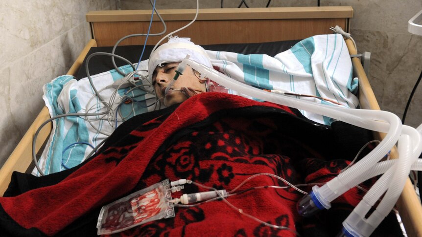 An badly injured man lies in a bed at a makeshift clinic in the city of Idlib