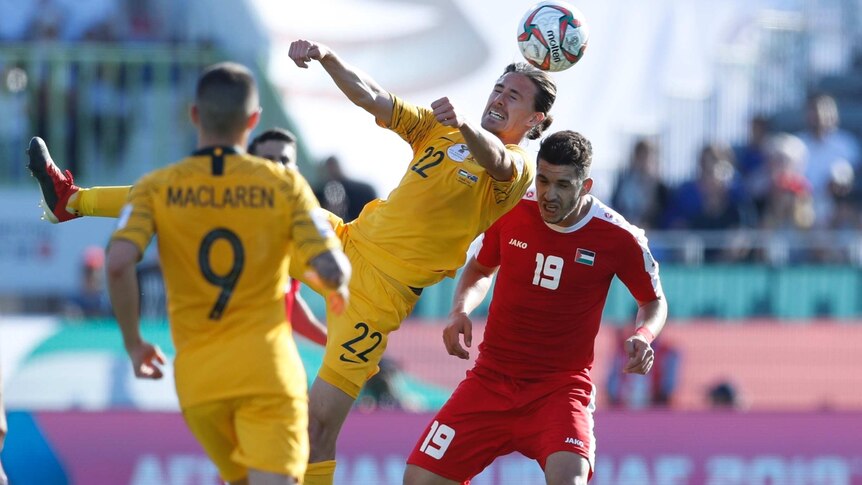 Jackson Irvine grimaces as he rises to head the ball ahead of Palestine's Mahmoud Wadi