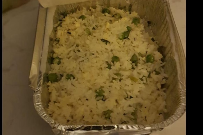 Alfoil container with rice and peas inside.