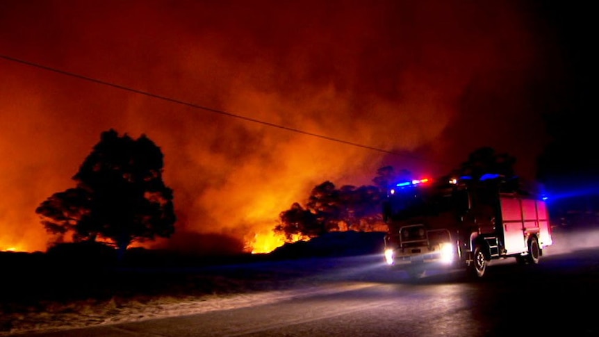 A fire truck parked on the road beside a bushfire at night at Stanthorpe.