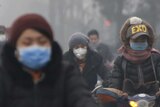 People wear protective masks while riding bikes in smog.