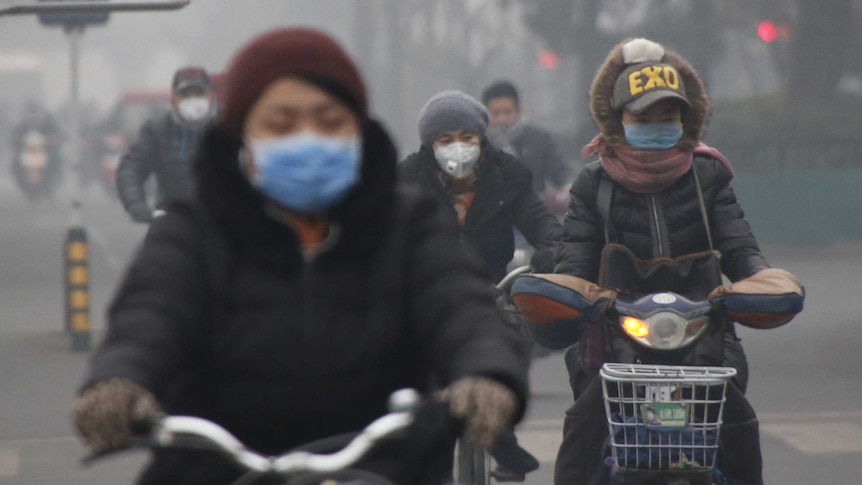 People wear protective masks while riding bikes in smog.