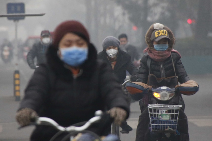 People wear protective masks while riding bikes in smog.