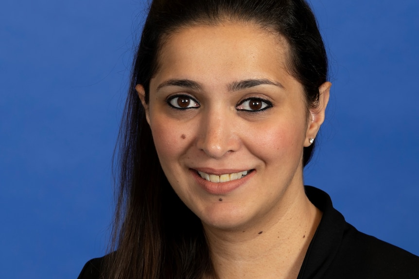 A woman smiling against a blue background