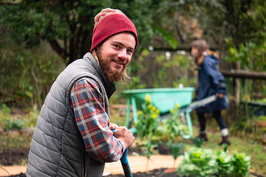 Jack Galluzzi with a shovel and person with wheelbarrow in the background.