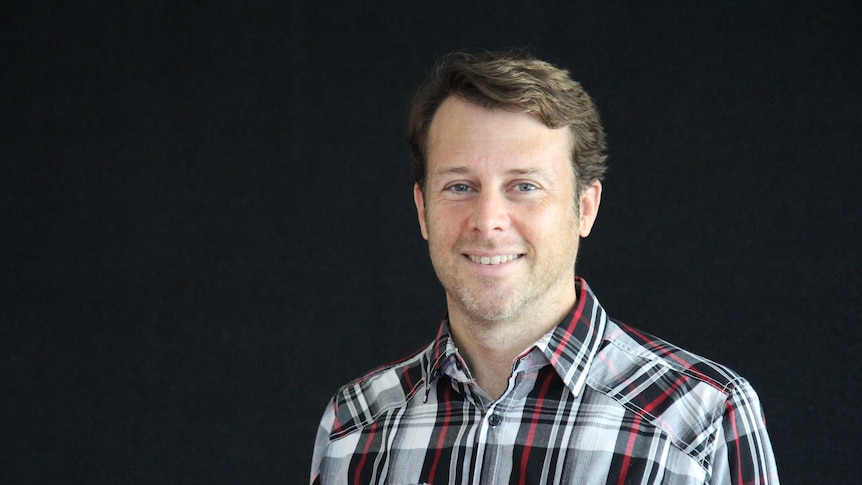 Portrait shot of a man in front of a black wall.